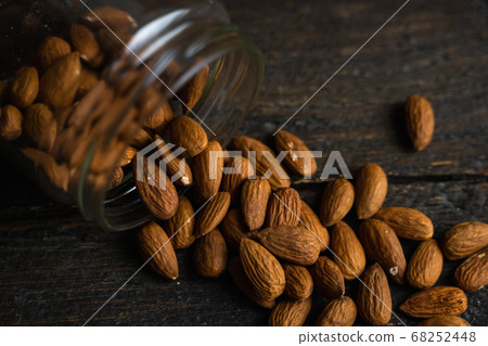 Almonds scattered on the wooden vintage table from a jar. Almond is a healthy vegetarian protein nutritious food. Almonds on rustic old wood. Almonds scattered on the wooden vintage table from a jar. Almond is a healthy vegetarian protein nutritious food. Almonds on rustic old wood. 68252448
