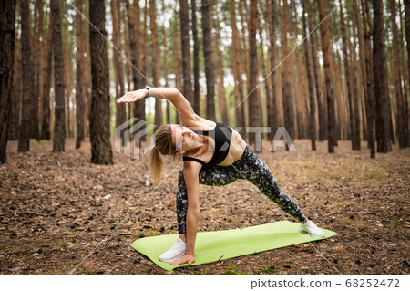 Woman in sportswear does workout outdoors, weight loss exercise. Yoga, concept of functional workout 68252472