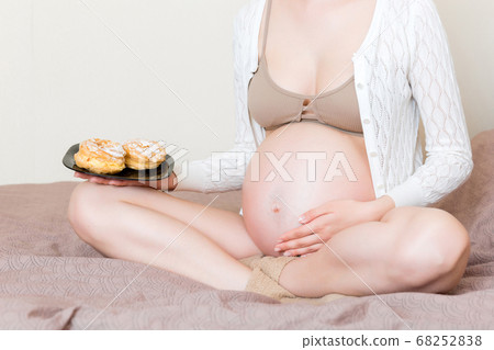 Close up of young pregnant woman enjoys eating Close up of young pregnant woman enjoys eating 68252838