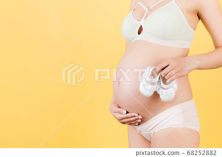 Close up of pregnant woman holding a pair of shoes Close up of pregnant woman holding a pair of shoes 68252882