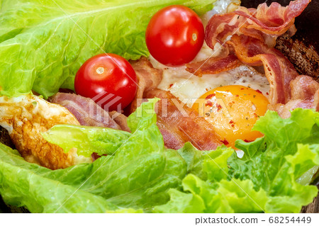 Breakfast fried eggs, bacon tomatoes, salad background, texture. English Breakfast, keto diet 68254449