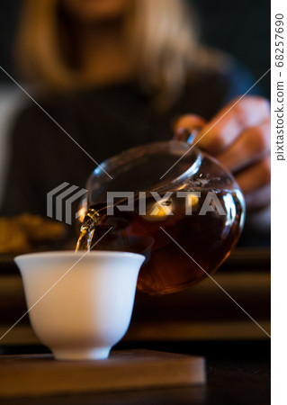 Traditional Chinese Tea Ceremony. Black or Red Tea pouring By a Blonde Caicasian girl into White pial cup on dark Table background Traditional Chinese Tea Ceremony. Black or Red Tea pouring By a Blonde Caicasian girl into White pial cup on dark Table background 68257690