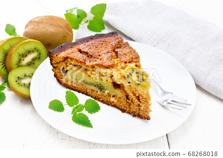 Pie with kiwi in plate on wooden light board 68268018