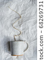 craft ceramic mug with sand texture  with brown wire as coffee smoke on white crumpled paper, handmade craft pottery, background 68269731