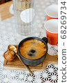 top view  hot black coffee in black ceramic cup on wooden tray put white table with red plastic cups and glass bottle of water on white table, copy space 68269734