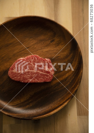 Raw beef fillet steak on an acacia plate on a wooden desk Raw beef fillet steak on an acacia plate on a wooden desk 68273036