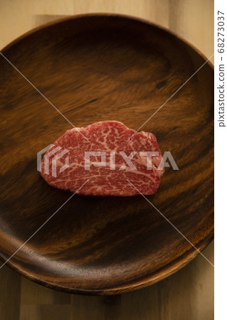 Raw beef fillet steak on an acacia plate on a wooden desk 68273037
