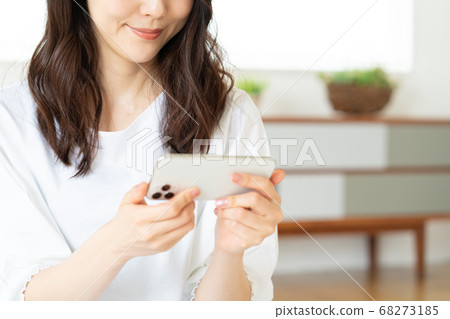 A young woman operating a smartphone in the living room 68273185