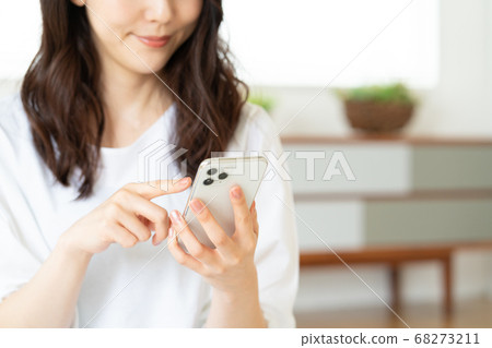 在客廳裡操作智能手機的年輕女子專注於智能手機 68273211
