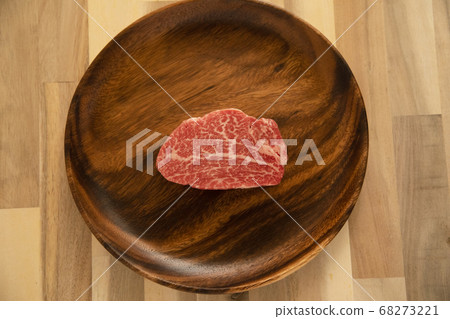 Raw beef fillet steak on acacia plate on wooden desk 68273221