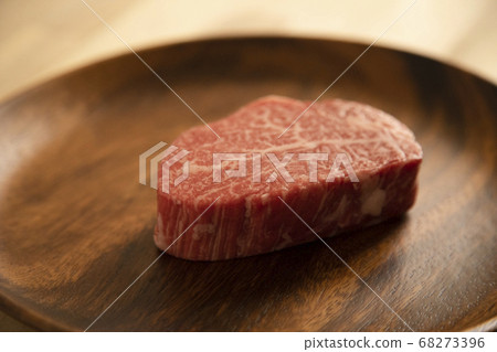 Raw beef fillet steak on acacia plate on wooden desk Raw beef fillet steak on acacia plate on wooden desk 68273396