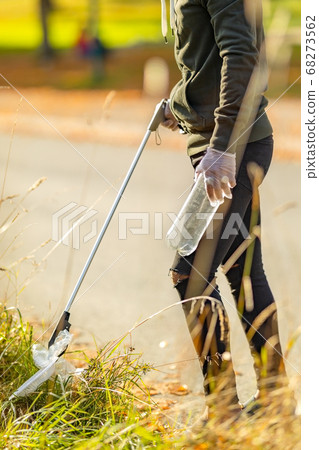 Male volunteer picking up plastic trash from grass Male volunteer picking up plastic trash from grass 68273562