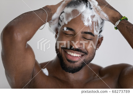 Close up smiling African American man washing hair with shampoo Close up smiling African American man washing hair with shampoo 68273789