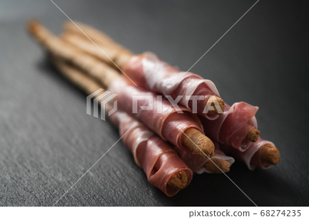 grissini breadsticks with prosciutto on slate background 68274235