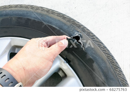Hand showing flat ruptured damaged tire wheel with 68275763