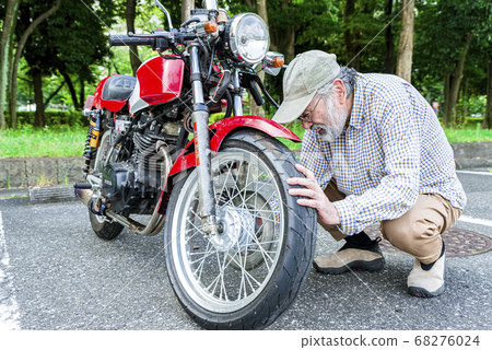 Bike life Senior rider maintaining a bike Bike life Senior rider maintaining a bike 68276024