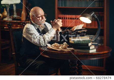 Elderly writer thinks at vintage typewriter Elderly writer thinks at vintage typewriter 68278474