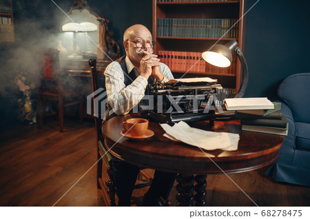 Elderly writer thinks at vintage typewriter Elderly writer thinks at vintage typewriter 68278475