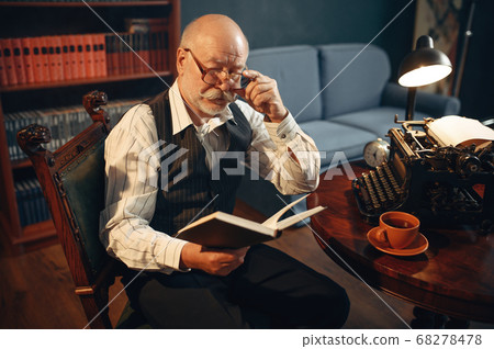Elderly writer reads work at vintage typewriter Elderly writer reads work at vintage typewriter 68278478