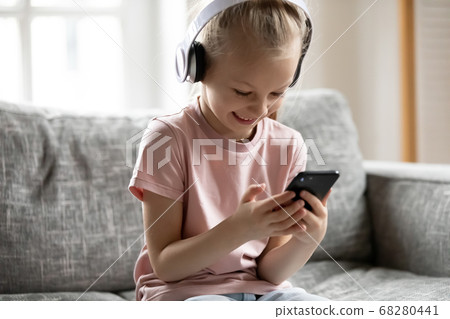 Little adorable blonde girl watching funny video on smartphone. Little adorable blonde girl watching funny video on smartphone. 68280441