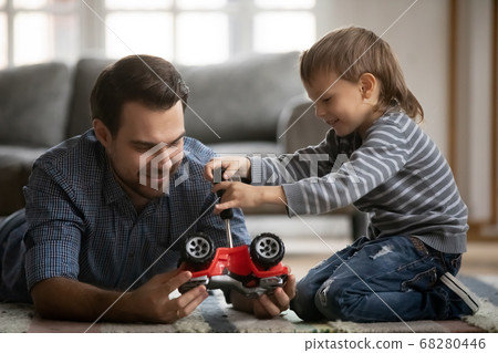 Happy family fixing car, enjoying playtime together at home. 68280446