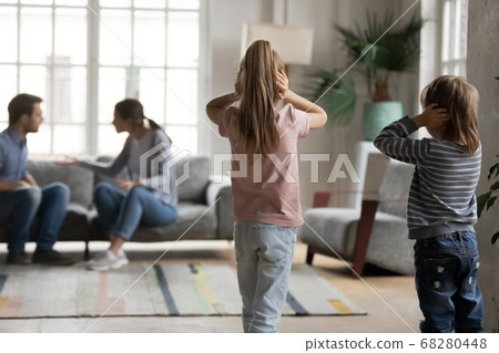 Unhappy little children looking at arguing parents. 68280448