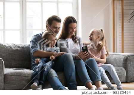 Smiling young woman showing funny video to husband and children. Smiling young woman showing funny video to husband and children. 68280454
