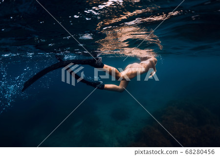 Sporty woman with fins swim in blue sea. Swimming in ocean 68280456