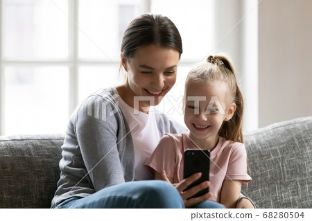 Smiling young mother showing funny mobile application to kid. Smiling young mother showing funny mobile application to kid. 68280504