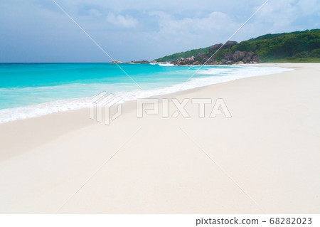 White sand beach with waves and hills with green 68282023