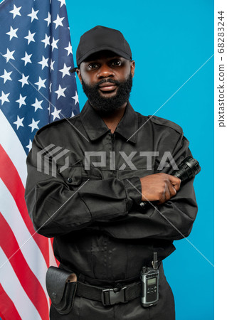 Bearded African-american male security in black uniform crossing arms on chest 68283244
