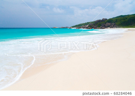 White sand beach with waves and hills with green 68284046