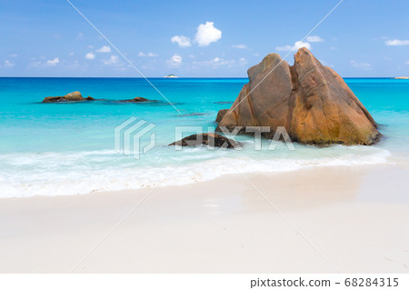 Beach with blue water and blue sky and some rocks 68284315