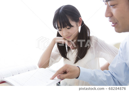 Daughter studying and father teaching Daughter studying and father teaching 68284876