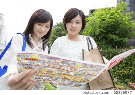 Housewife looking at a supermarket leaflet 68286977