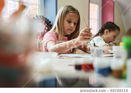 Beautiful girls painting at desk in class room Beautiful girls painting at desk in class room 68288218