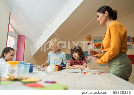 Cheerful kids enjoying art lesson with teacher Cheerful kids enjoying art lesson with teacher 68288228