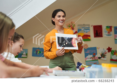 Happy beautiful woman holding art courses for kids Happy beautiful woman holding art courses for kids 68288243