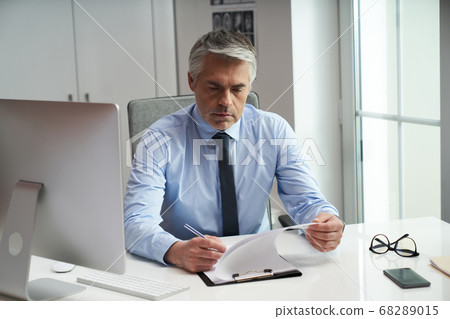 General practitioner checking his list of appointments 68289015