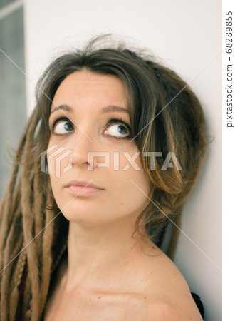 Indoors female portrait of a woman with dreadlocks hairstyle and smoky eyes makeup Indoors female portrait of a woman with dreadlocks hairstyle and smoky eyes makeup 68289855