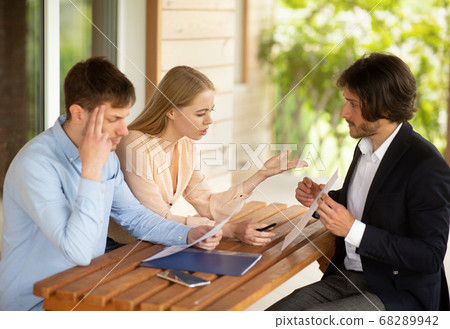 Millennial family disappointed at bad rental terms and property manager at table on house porch Millennial family disappointed at bad rental terms and property manager at table on house porch 68289942