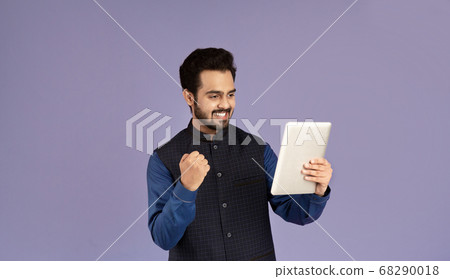 Young Indian guy with tablet computer gesturing YES on violet background 68290018