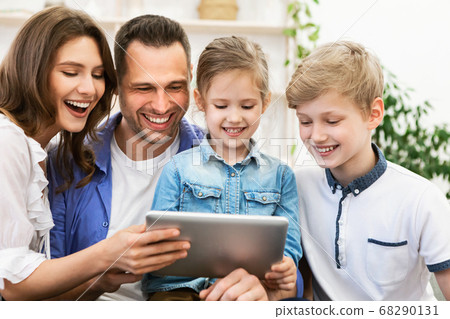 Joyful Family Using Digital Tablet Laughing Watching Movie At Home Joyful Family Using Digital Tablet Laughing Watching Movie At Home 68290131