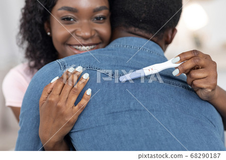 Closeup of african woman with pregnancy test hugging husband Closeup of african woman with pregnancy test hugging husband 68290187