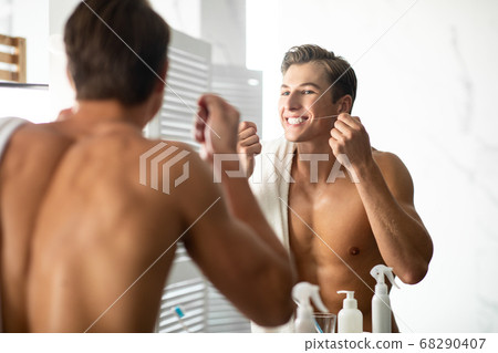 Handsome young man using dental floss in bathroom Handsome young man using dental floss in bathroom 68290407