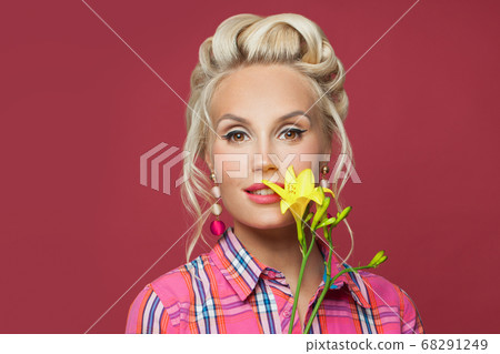 Pretty pinup woman with yellow flower on red 68291249