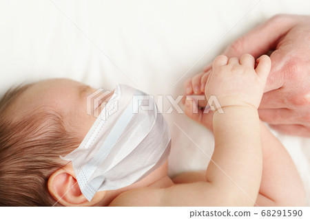 Baby in protective madical face mask holding 68291590