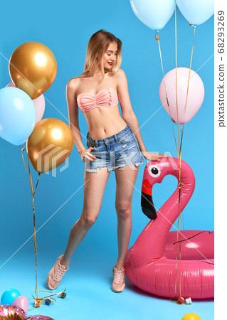 slim graceful charming girl with long blonde looking at inflatable flamingo. slim graceful charming girl with long blonde looking at inflatable flamingo. 68293269