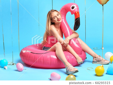blonde woman in stylish casual clothes sitting on inflatable flamingo blonde woman in stylish casual clothes sitting on inflatable flamingo 68293315