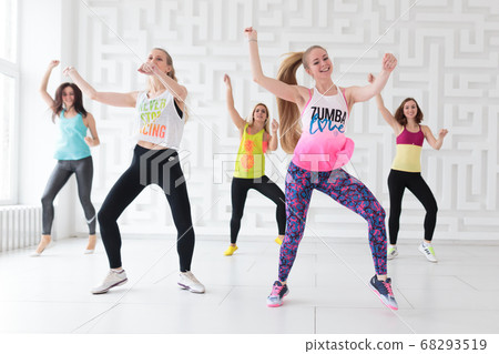 Group of young happy women wearing colorful sportswear dancing at dance class Group of young happy women wearing colorful sportswear dancing at dance class 68293519